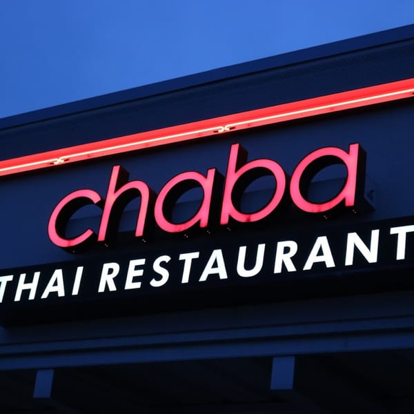 Chaba Thai Restaurant sign with glowing red letters against a dark blue sky.