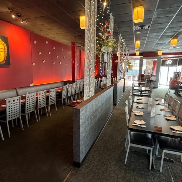 Interior of Chaba Thai Restaurant with red walls, Buddha art, and multiple dining tables with chairs.